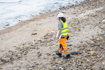 Environmental Scientist Inspecting Polluted Coastline, Worker in Safety Gear Walking on Rocky Beach...