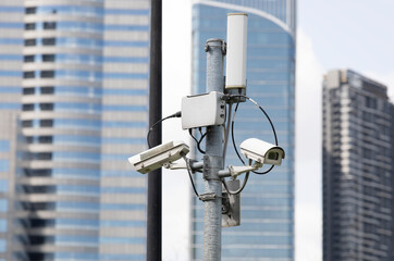 Security cameras on pole with modern building in background.