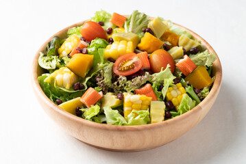 Colorful vegetable salad in a rustic wooden bowl on white background, Healthy, fresh, plant- based eating concept
