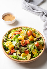 Colorful vegetable salad in a rustic wooden bowl with Japanese sesame dressing on white background, Healthy, fresh, plant based eating concept
