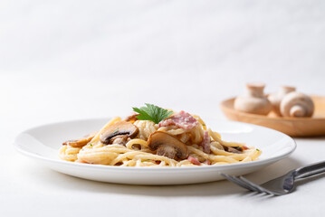 Spaghetti carbonara with ham, bacon and champignon mushroom on plate with white background, Italian food
