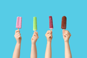 Female hands with different sweet ice-cream on blue background
