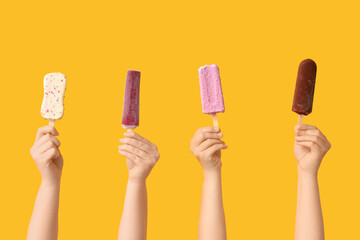 Female hands with different sweet ice-cream on yellow background