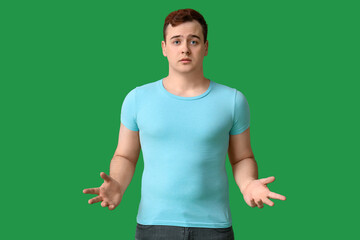 Young shocked overweight man on green background. Weight gain concept