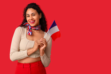 Beautiful young happy African-American woman with flag of France on red background