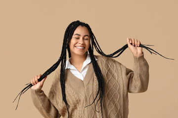 Beautiful young happy African-American woman on beige background