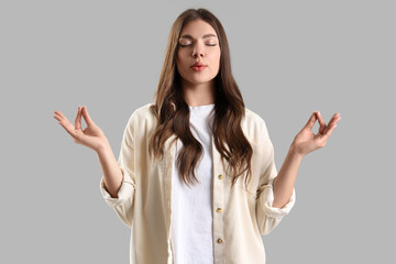 Young woman trying to calm down while having panic attack on light background