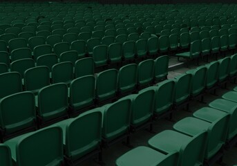 Naklejka premium A large section of an empty arena or theater, with rows of dark green seats
