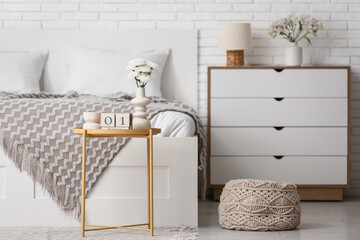 Table with cube calendar, flowers and candle in stylish bedroom