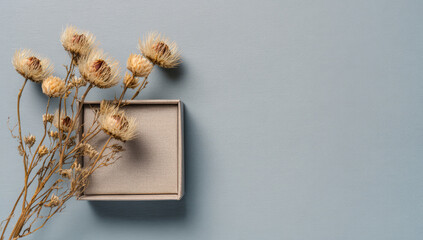Dried flowers in decorative box on blue background create serene atmosphere