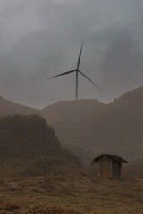 A windmill, a hut, and a stormy, foggy day