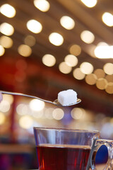 Sweetening tea in a cozy cafe setting with warm lights