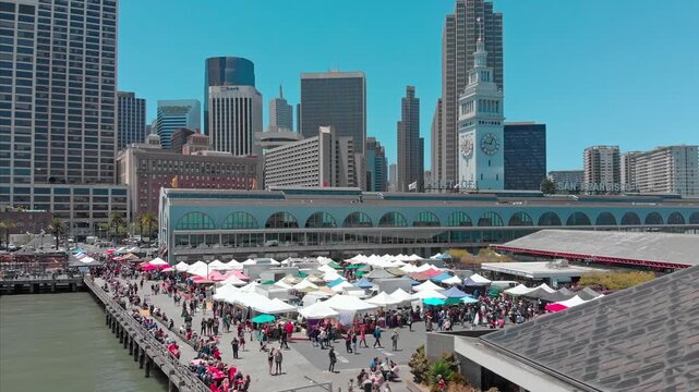 San Francisco, USA: A bustling farmers market at the Ferry Building Marketplace draws crowds of people to shop for local produce and goods on a sunny day.