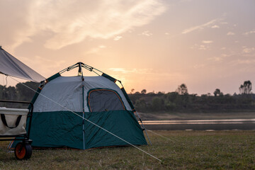 Camping tent set up near a lake during sunset