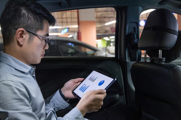 Man using tablet with business charts inside a car