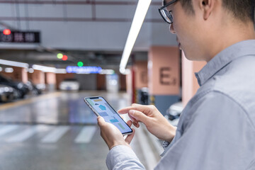 Man using mobile phone in parking garage checking parking information