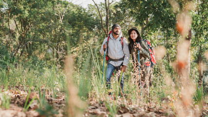 A couple is hiking along a forest trail on a beautiful day, enjoying nature and their outdoor adventure perfect for themes of travel, hiking, and togetherness.