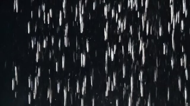 Seamlessly looped close-up animation of falling rain with realistic raindrops, vertical rainfall resembling a rain wall. Real rainstorm VFX insert style, dark black background, 4K resolution, high det