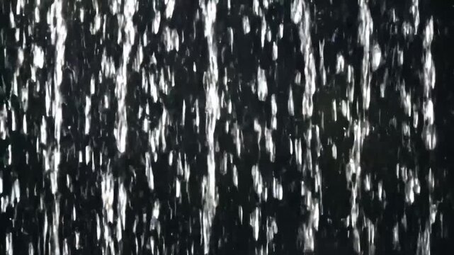 Seamlessly looped close-up animation of falling rain with realistic raindrops, vertical rainfall resembling a rain wall. Real rainstorm VFX insert style, dark black background, 4K resolution, high det
