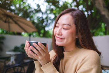 Portrait image of a woman holding and drinking coffee in the outdoors cafe