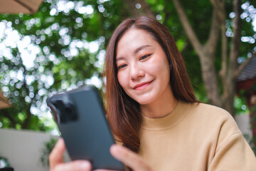 Portrait image of a woman holding and using mobile phone in the outdoors