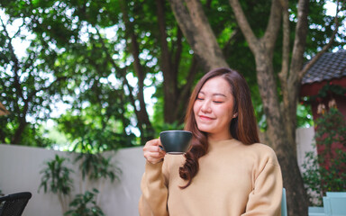 Portrait image of a woman holding and drinking coffee in the outdoors cafe
