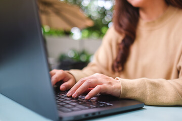 Closeup image of a woman working and typing on laptop computer keyboard in the outdoors