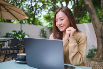 Portrait image of a woman working on laptop computer in the outdoors
