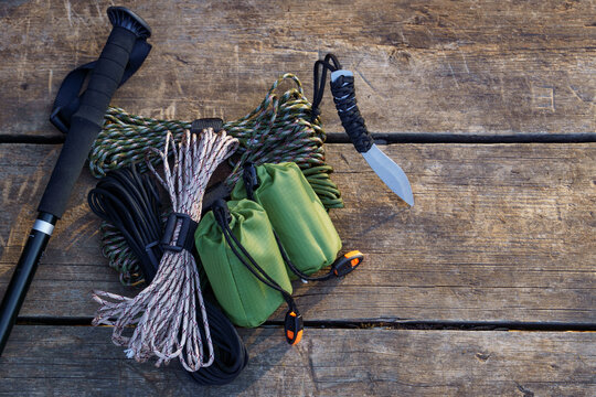 Trekking pole, knife, paracord and stuff sacks lying on wooden table