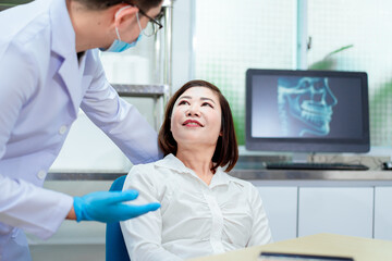 An Asian male dentist is examining a female patient’s teeth in a dental clinic, using dental instruments to ensure oral health and provide professional dental care