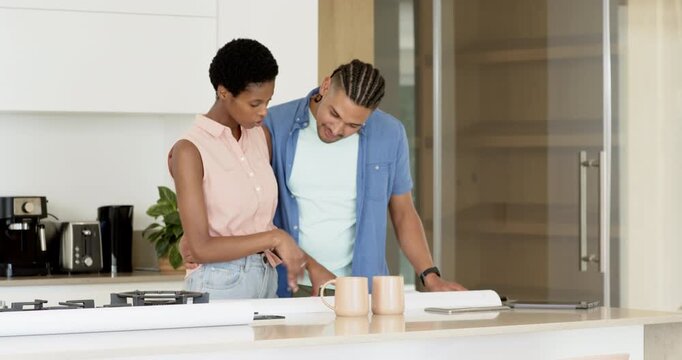 Upon seeing markup on plans Diverse couple leaning over island scrolling tablet for renovation