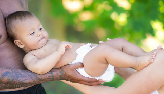 Mixed race family outdoor portrait. Mixed race parents with baby child on nature. Mixed race Portrait of happy african american or hispanic father and caucasian mother with mixed race baby.