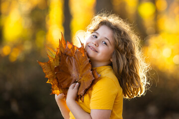 Autumn Child Face. Kid hold Fall Yellow Leaves. Little Child In Beautiful Autumn Park Outdoor. Kids play in autumn park. Child boy with oak maple leaf. Fall foliage. Kids face in autumn fall close up.
