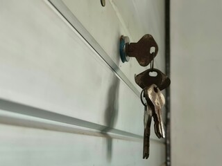 Close-up of old rusty keys hanging from a lock on a metal garage door