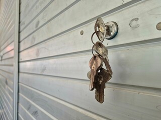 Close-up of old rusty keys hanging from a lock on a metal garage door