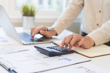 Fototapeta premium Account finance, asian young business man hand using calculator, laptop computer for calculate budget, cost and income of company from paperwork, plan spend money expenses, working on desk at home.