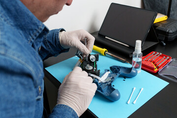 Electronic technician wearing gloves repairing a broken joystick using a screwdriver, soldering...