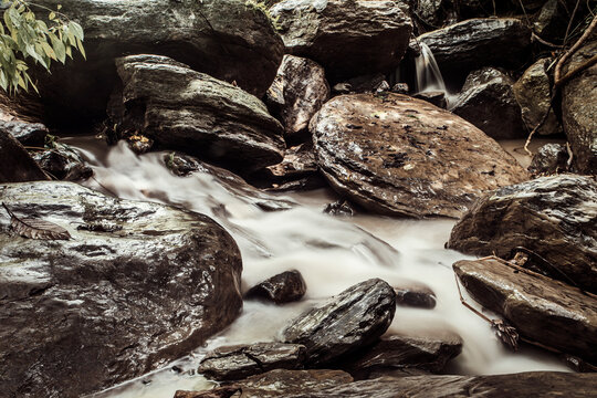 Rushing Water Cascading Through Granite Boulders. Bangladesh is home to several beautiful waterfalls, each with its unique charm. Waterfall Cascading Over Rocks in Serene Forest Setting.