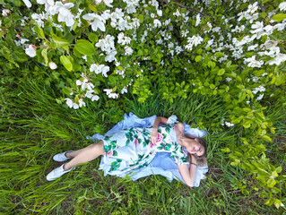 Blonde woman relaxing among blooming flowers in a lush green field while enjoying a peaceful moment...