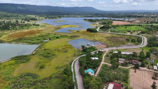Drone footage of aerial view of Lam Phra Phloeng reservoir and surrounding farmland in Wang Nam Khiao, Nakhon ratchasima, Thailand. Scenic landscape of countryside with curved rural roads 