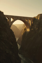 Generative AI Ancient Stone Arch Bridge Over River Stone bridge Arch bridge Gorge Canyon Landscape Architecture Sunset Golden hour Travel Outdoors Water Cliff Mountain - Unique Design