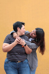Two dark-skinned Latina lesbians are a couple and show their love with kisses and hugs to celebrate...