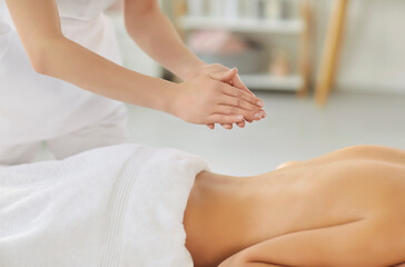 Close up of a female therapist readies for back massage session with patient during spa treatment...