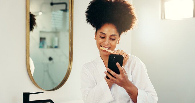 Phone, dental hygiene and woman brushing teeth in bathroom with networking on mobile app. Oral care, technology and female person cleaning mouth for morning routine with social media on cellphone. - Powered by Adobe