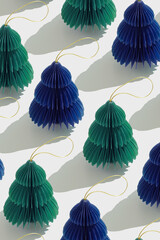 Minimal pattern of blue green paper Christmas ornaments shaped fie tree on white, stylish holidays...