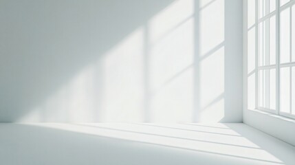 Fototapeta premium Minimal white interior with sunlight streaming through large windows, casting geometric shadows on floor and walls for modern design use.