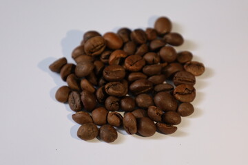 Roasted brown coffee beans, isolated on a white background, form a heap, ready for a rich, dark espresso drink