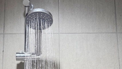 Water flowing from overhead shower in tiled bathroom