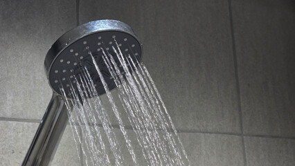 Handheld shower head spraying water in bathroom