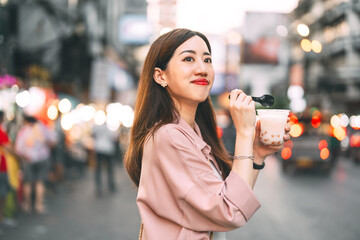 Happy adult asian traveler woman eating sweet taiwan boba dessert menu at Yaowarat road